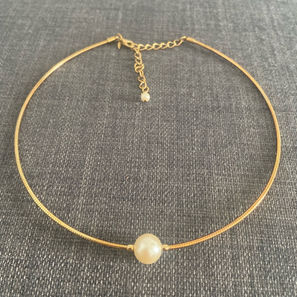 Gold necklace with a pearl in the center of it